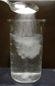 Spooning salt into a beaker of water